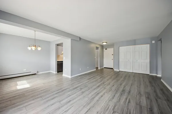 an empty room with wooden floor chandelier and glass door