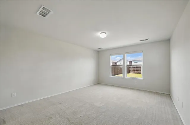 an empty room with a window and a kitchen