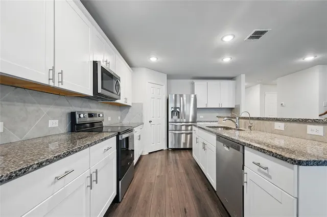 a large kitchen with stainless steel appliances granite countertop a lot of counter space a sink and dishwasher a stove top oven with wooden floor