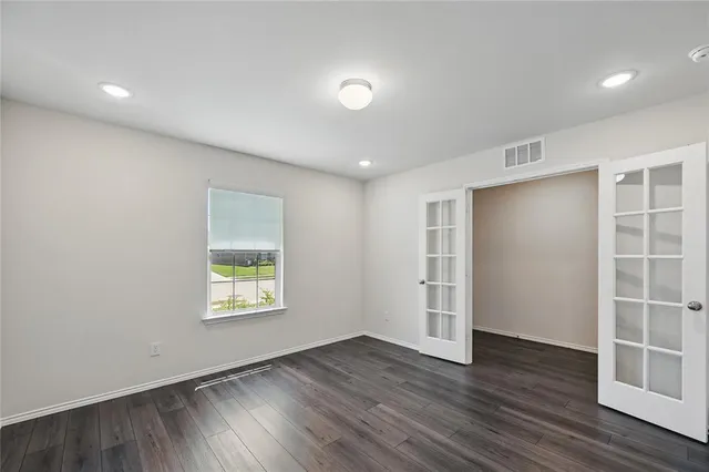 an empty room with wooden floor and windows