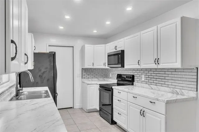 a kitchen with granite countertop white cabinets and stainless steel appliances