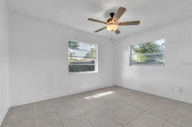 an empty room with windows and fan