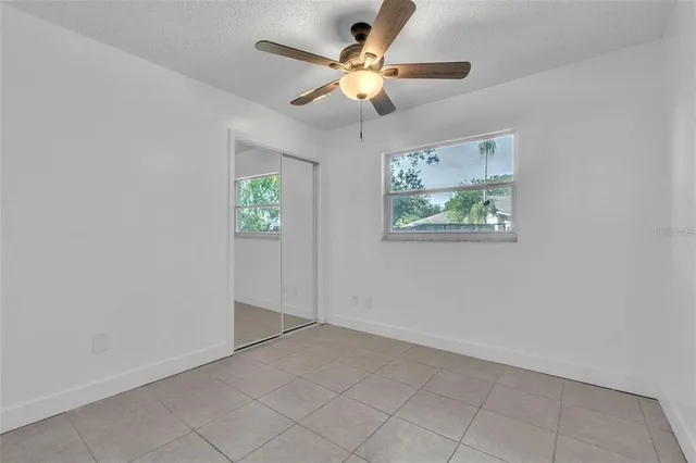an empty room with windows and fan