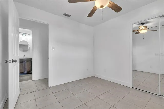 an empty room with closet and a chandelier fan