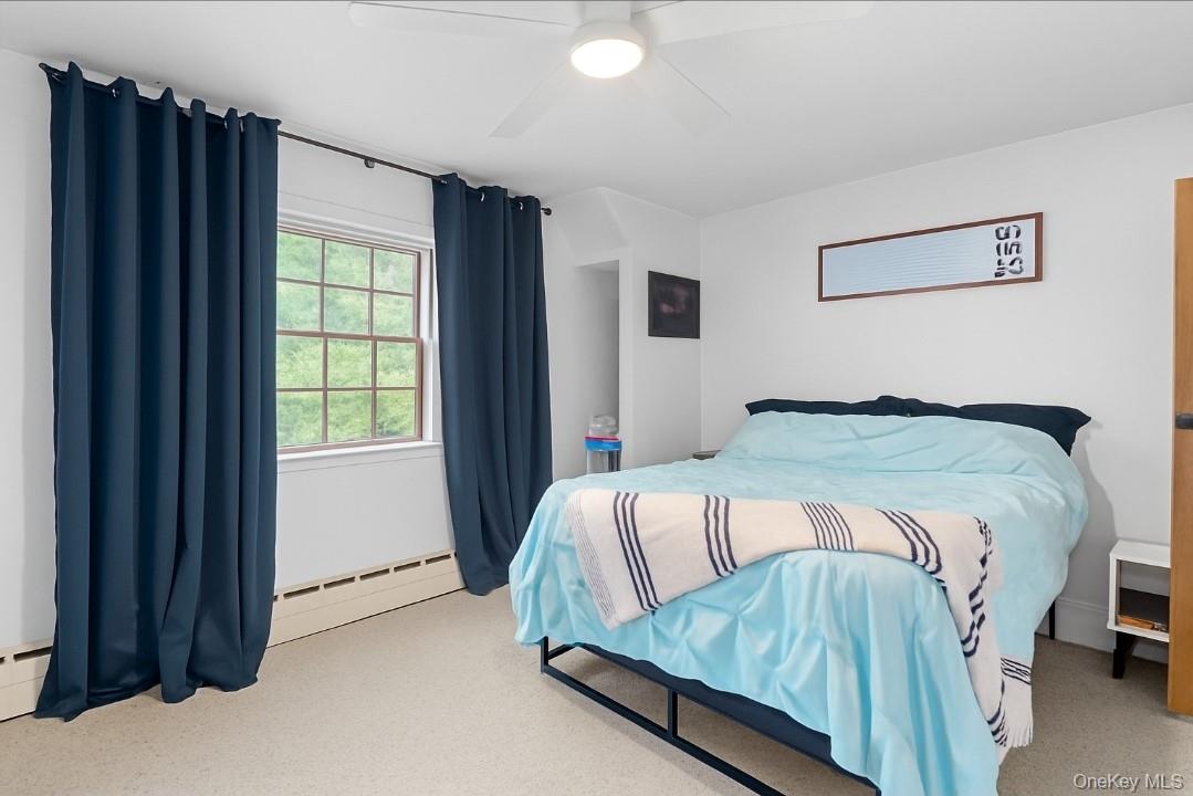 568 Old Liberty Road Monticello, NY 12701 - Photo 18 of 31 Primary bedroom featuring baseboard heating and ceiling fan. Large walk-in closet.