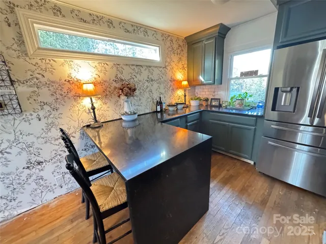 a kitchen with stainless steel appliances granite countertop a table chairs and a refrigerator