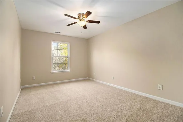 an empty room with windows and chandelier fan