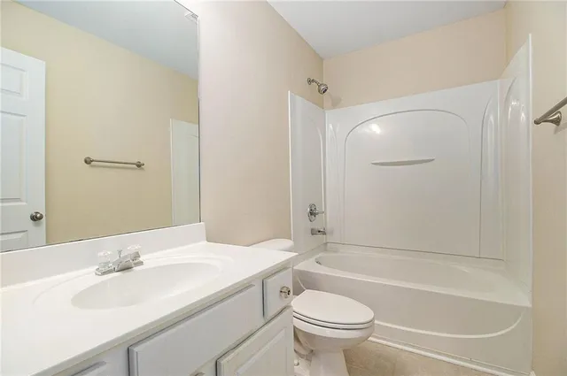 a bathroom with a granite countertop bathtub shower sink vanity mirror and toilet