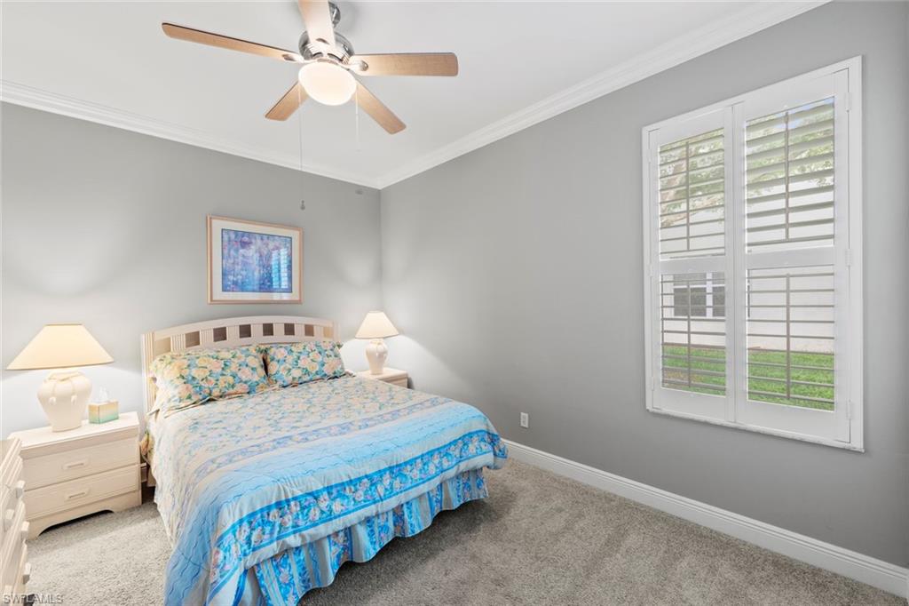 9057 Whitfield Drive Estero, FL 33928 - Photo 19 of 32 a bedroom with a bed a chandelier and a window