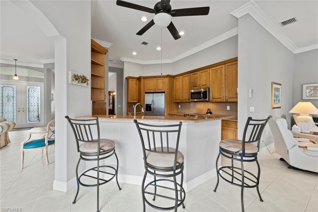 9057 Whitfield Drive Estero, FL 33928 - Photo 10 of 32 a kitchen with stainless steel appliances a dining table chairs and a refrigerator