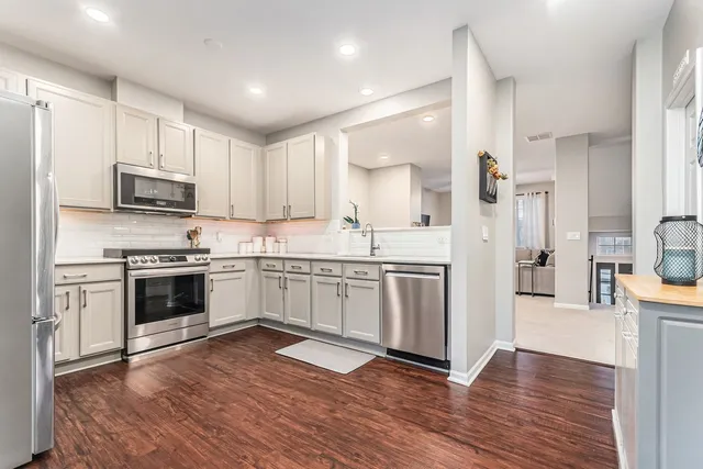 a kitchen with stainless steel appliances white cabinets a sink a stove a refrigerator and a microwave