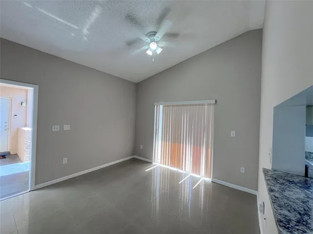 an empty room with a chandelier fan and windows