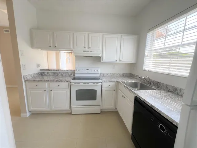 a kitchen with granite countertop white cabinets and white appliances