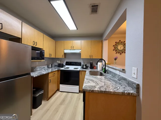 a kitchen with stainless steel appliances granite countertop a refrigerator stove microwave and sink