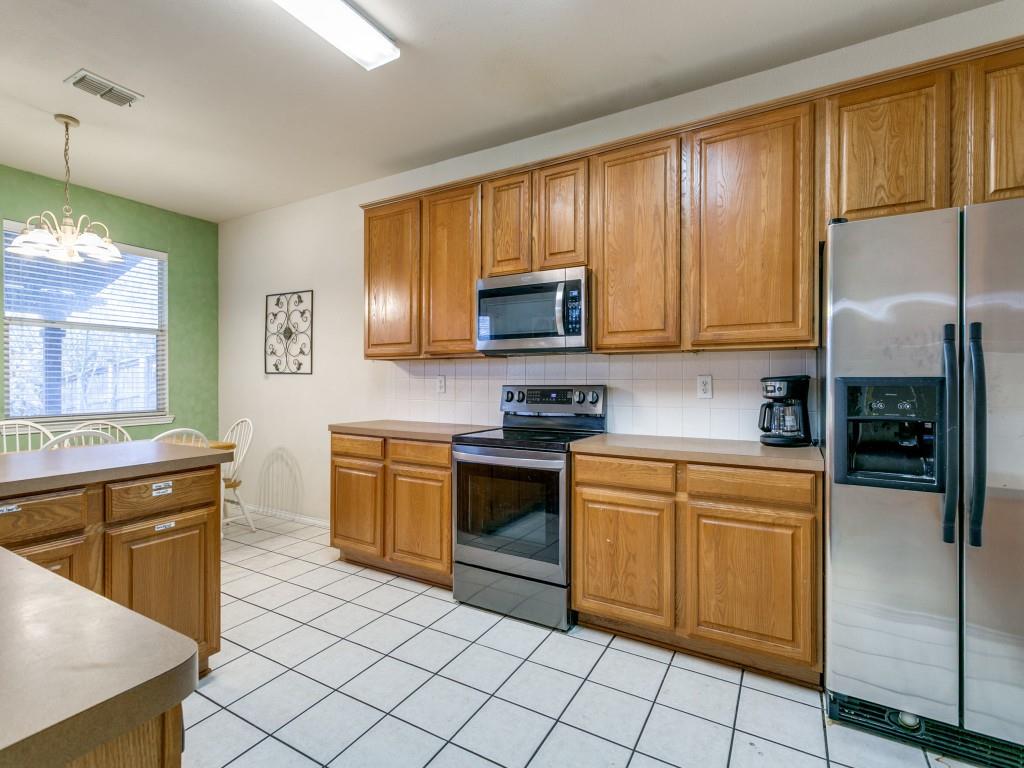 1105 Riverside Drive Lewisville, TX 75067 - Photo 18 of 40 a kitchen with stainless steel appliances granite countertop wooden cabinets a stove top oven a sink and dishwasher