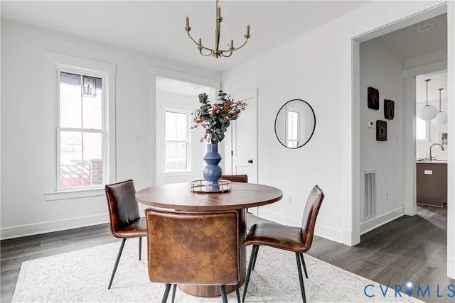 a dining room with chandelier and wooden floor