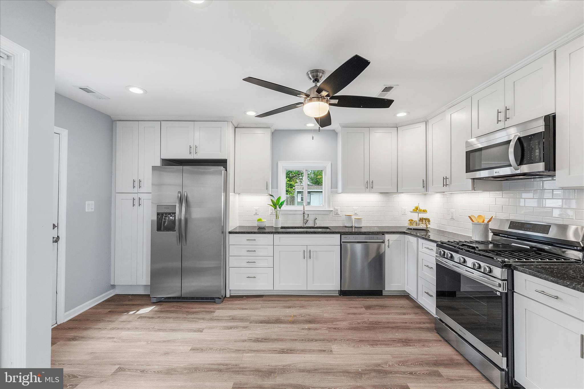 7400 Belclare Road Baltimore, MD 21222 - Photo 2 of 33 a kitchen with stainless steel appliances granite countertop a stove a refrigerator a sink a microwave and wooden cabinets
