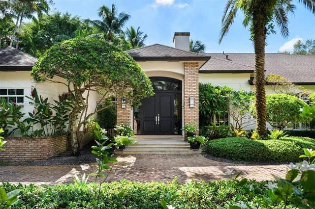 a front view of a house with a yard and potted plants