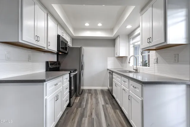 a kitchen with granite countertop a sink a counter space stainless steel appliances and cabinets