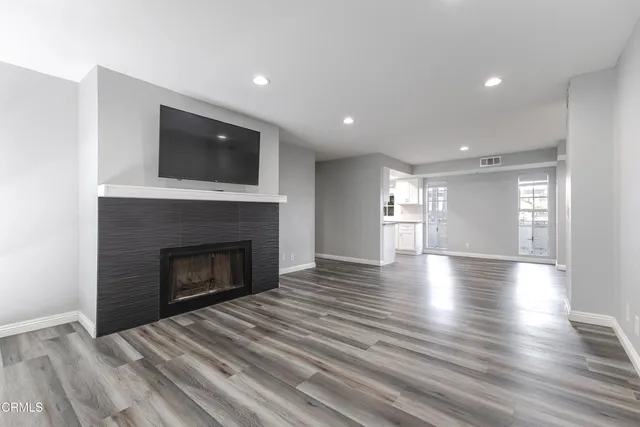 a view of an empty room with wooden floor fireplace and a window