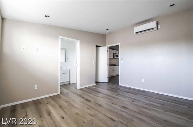 2201 Fairfield Avenue, Unit 9 Las Vegas, NV 89102 - Photo 7 of 7 Unfurnished bedroom with wood finished floors, a wall unit AC, and ensuite bathroom