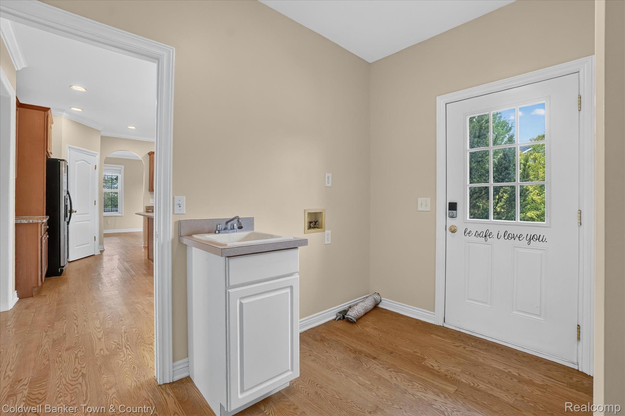 1725 Town Commons Drive Howell, MI 48855 - Photo 21 of 53 Utility area featuring wood-finish flooring, a white cabinet with an integrated sink, and an exterior door with window panes