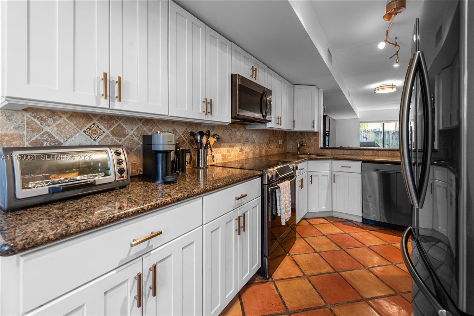 7890 Southwest 86th Street, Unit 10 Miami, FL 33156 - Photo 6 of 32 a kitchen with stainless steel appliances granite countertop a stove a sink and a microwave