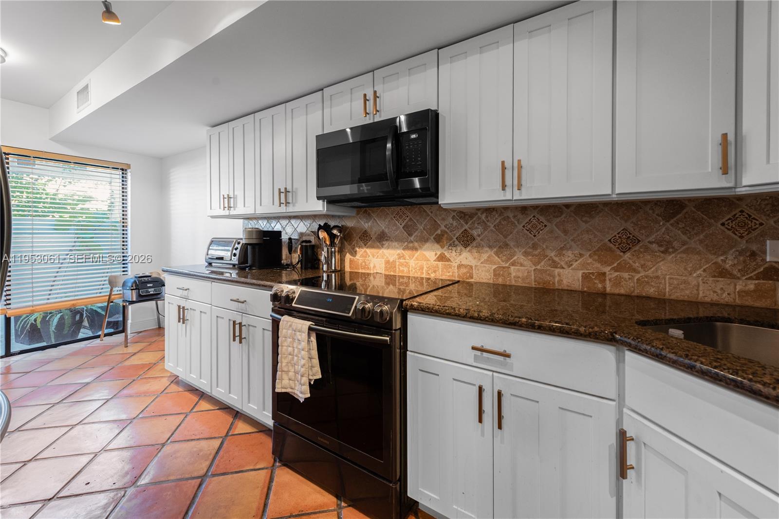7890 Southwest 86th Street, Unit 10 Miami, FL 33156 - Photo 8 of 32 a kitchen with stainless steel appliances granite countertop a sink a stove a microwave and cabinets