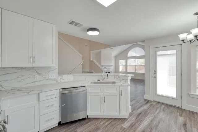 a kitchen with white cabinets and sink