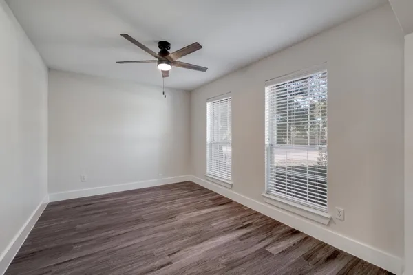 an empty room with a chandelier fan and windows