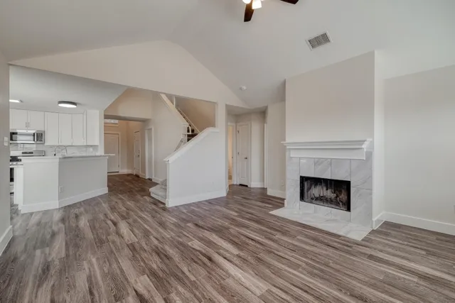 a view of a livingroom with wooden floor and a kitchen