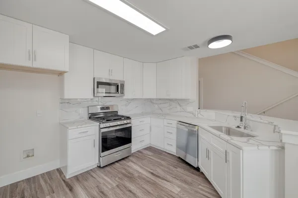 a kitchen with white cabinets and sink