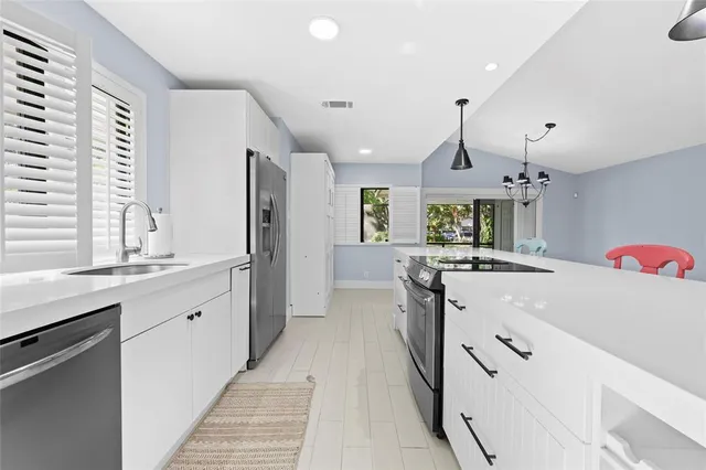 a large kitchen with granite countertop a large stove a sink dishwasher and a refrigerator with wooden floor