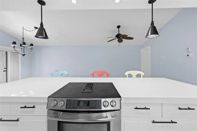 a stove a kitchen island with a stove a chimney a sink and wooden floor