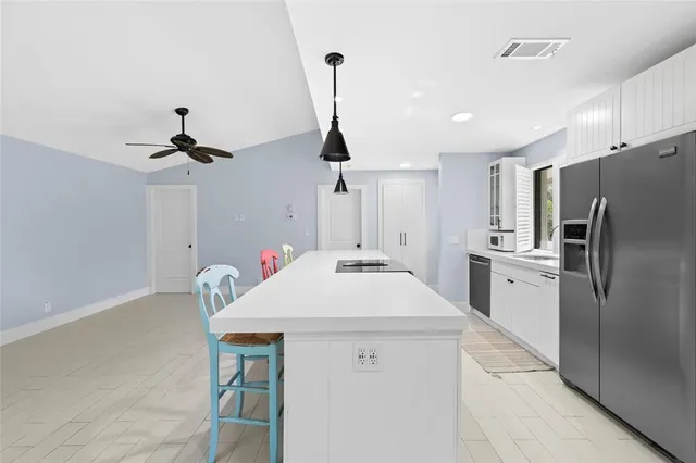 a kitchen with a sink a refrigerator and chairs