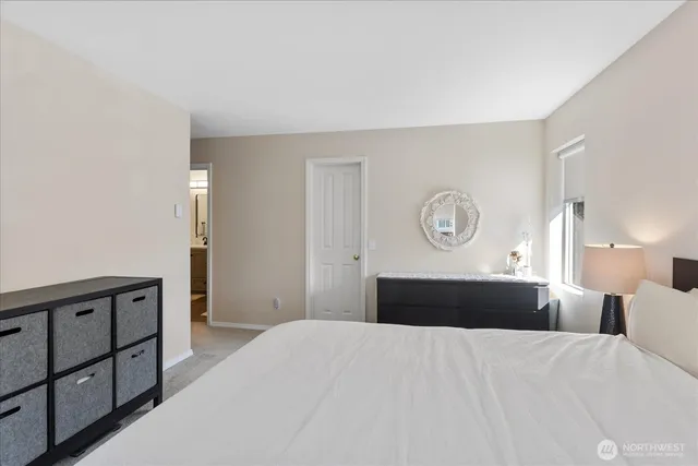 a bedroom with a bed and a lamp on dresser