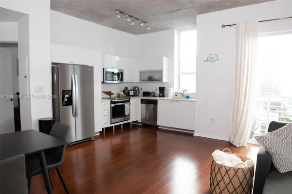 a kitchen with stainless steel appliances wooden floor and a refrigerator