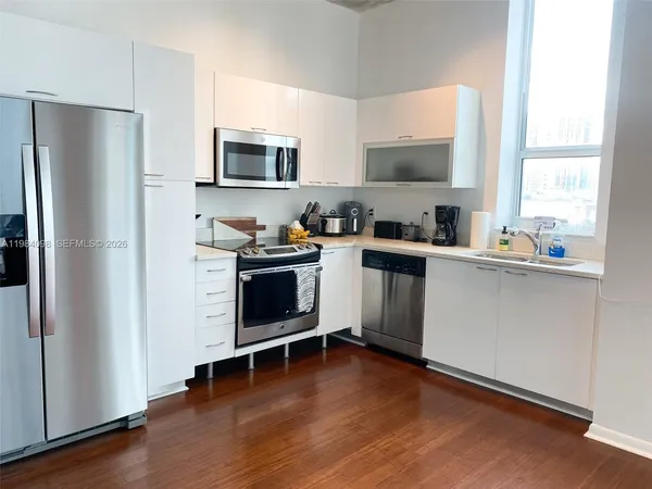 a kitchen with appliances a sink cabinets and a window