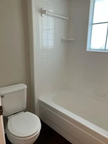 a white toilet and tub sitting next to a window