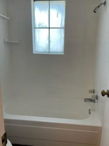a bathroom with a bathtub window and shower