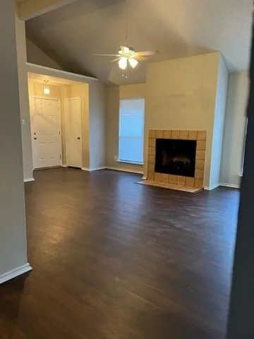 an empty room with wooden floor fireplace and windows