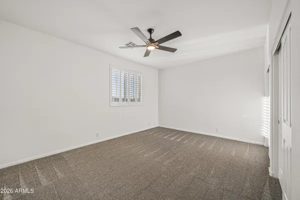 an empty room with windows and fan
