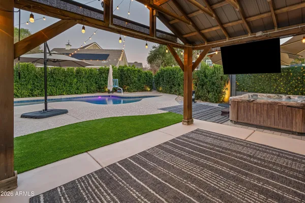 a view of a backyard with table and chairs under an umbrella with a small yard