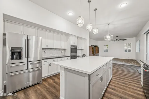 a kitchen with a refrigerator a sink and dishwasher with white cabinets