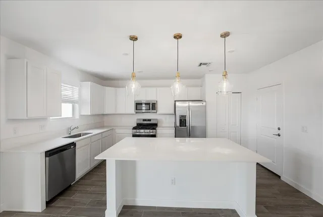 a kitchen with stainless steel appliances kitchen island granite countertop a sink a window and chairs