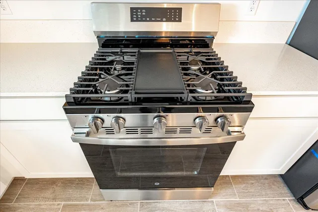 a large kitchen with stainless steel appliances kitchen island a large counter top and a wooden floors