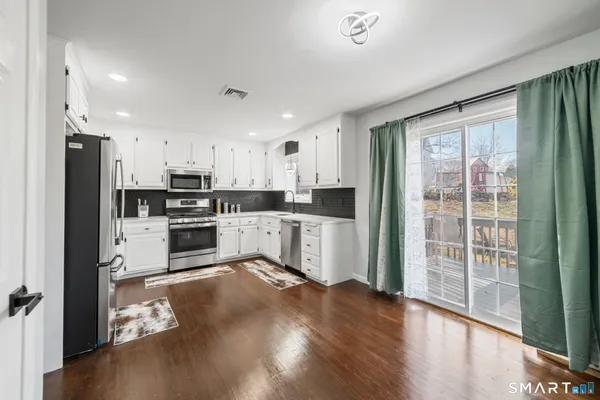 a kitchen with granite countertop a refrigerator stove top oven and cabinets