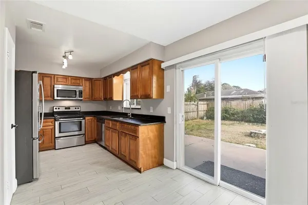 a kitchen with stainless steel appliances granite countertop a refrigerator and wooden cabinets
