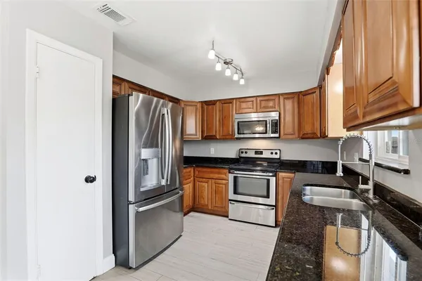 a kitchen with stainless steel appliances granite countertop a refrigerator stove top oven and sink