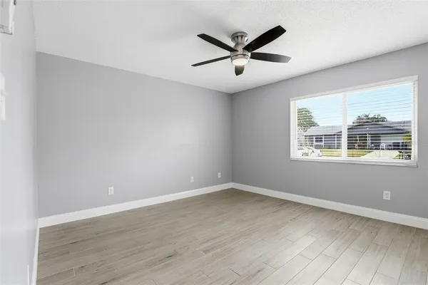an empty room to hallway with wooden floor closet and windows